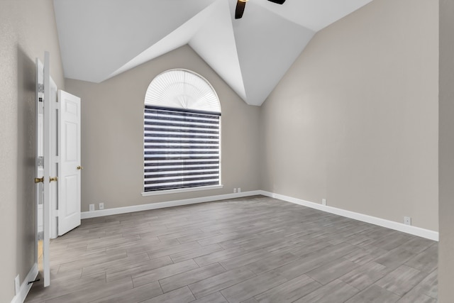 unfurnished room with a ceiling fan, vaulted ceiling, baseboards, and wood finished floors