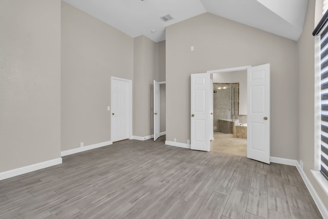 unfurnished bedroom with high vaulted ceiling, baseboards, visible vents, and wood finished floors