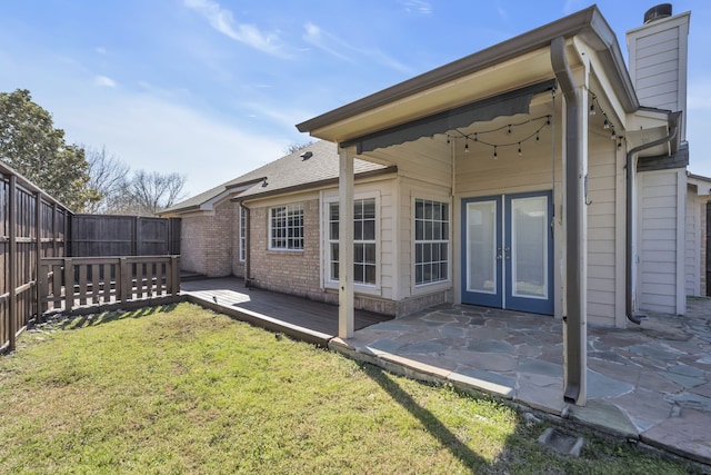 rear view of house featuring a fenced backyard, a chimney, a yard, a patio area, and brick siding