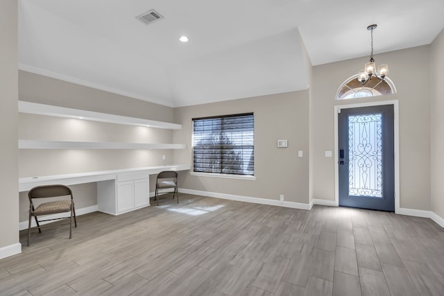 entrance foyer featuring visible vents, built in desk, light wood finished floors, and an inviting chandelier