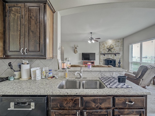 kitchen with dark brown cabinetry, a fireplace, a sink, open floor plan, and dishwasher