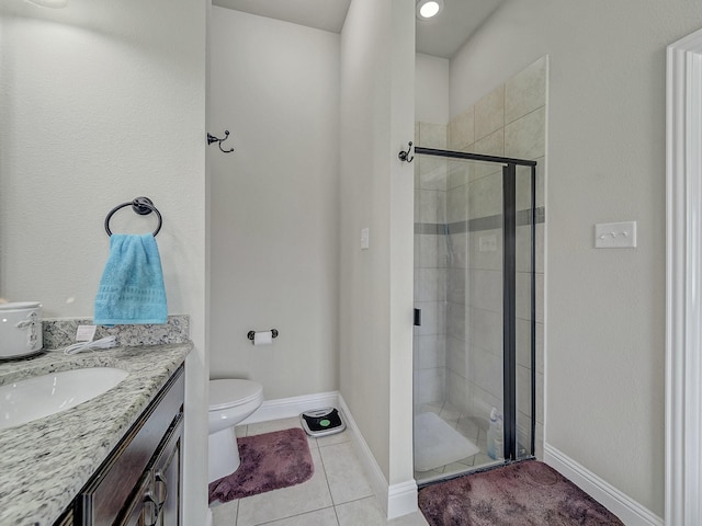 bathroom featuring toilet, a stall shower, vanity, baseboards, and tile patterned floors