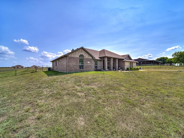 rear view of property with brick siding, a lawn, and fence