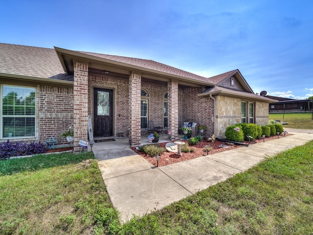 view of front of home with brick siding, a shingled roof, and a front yard