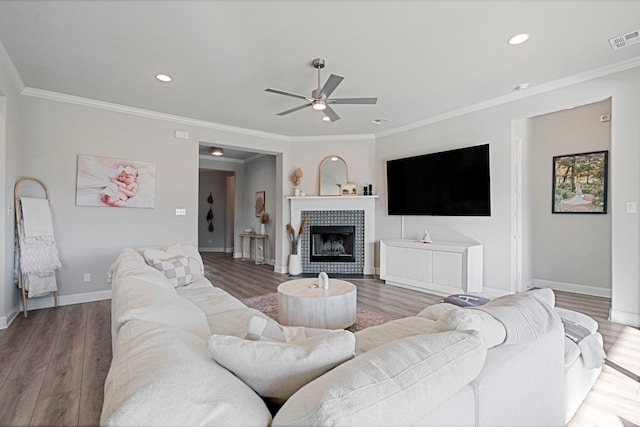 living room featuring ornamental molding, visible vents, and a tiled fireplace