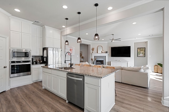 kitchen featuring appliances with stainless steel finishes, light wood-style flooring, a sink, and visible vents