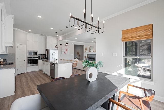 dining area featuring ornamental molding, a fireplace, and wood finished floors