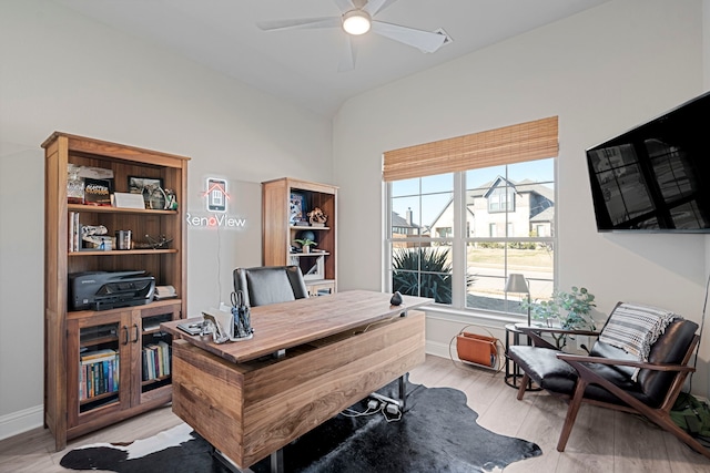 home office featuring lofted ceiling, light wood-style flooring, baseboards, and a ceiling fan