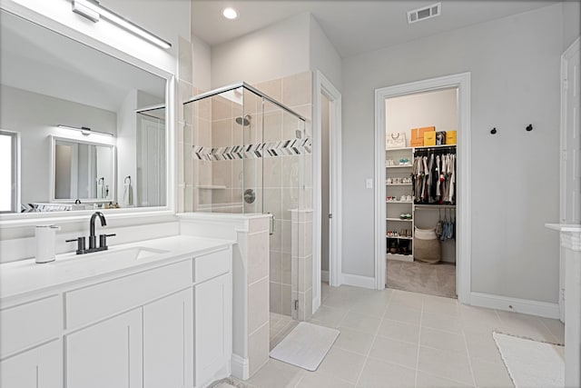 full bath with a walk in closet, visible vents, a stall shower, vanity, and tile patterned floors