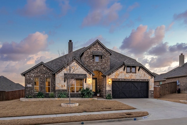 french provincial home with concrete driveway, brick siding, fence, and an attached garage