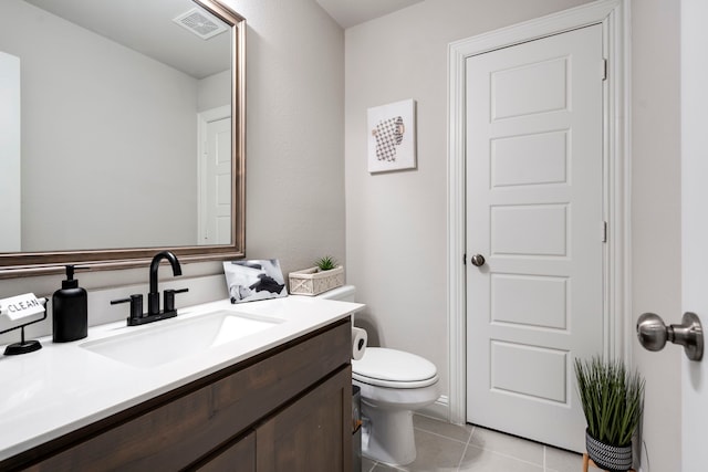 half bath with visible vents, vanity, toilet, and tile patterned floors