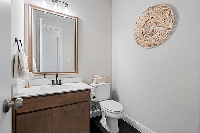 bathroom featuring baseboards, vanity, and toilet