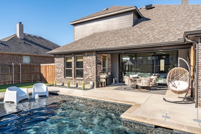 back of property featuring a shingled roof, brick siding, fence, and a patio