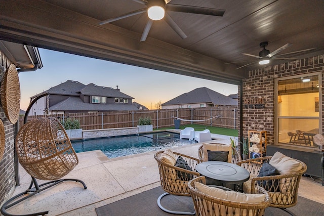 patio terrace at dusk featuring a fenced backyard and a fenced in pool