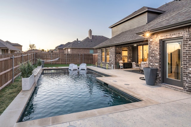 pool at dusk with a patio, a fenced backyard, and a fenced in pool