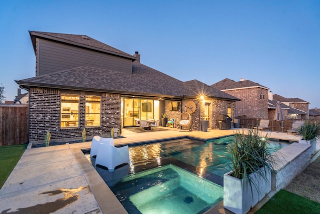 view of swimming pool featuring a patio area, fence, and a pool with connected hot tub