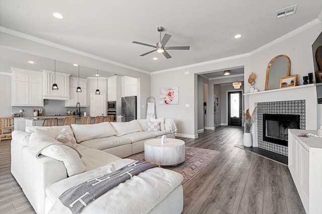 living room with baseboards, wood finished floors, visible vents, and crown molding