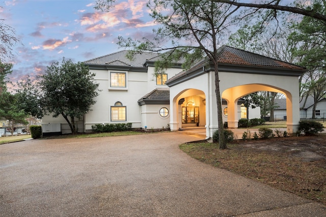 mediterranean / spanish-style home with driveway, a tile roof, and stucco siding