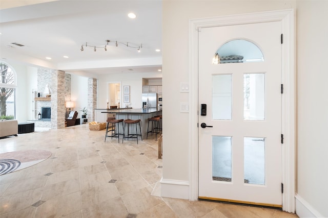 entryway featuring recessed lighting, visible vents, baseboards, a stone fireplace, and light tile patterned flooring