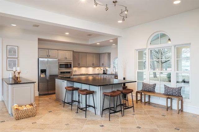 kitchen with dark countertops, appliances with stainless steel finishes, a sink, and gray cabinetry