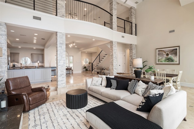 living room featuring decorative columns, stairs, visible vents, and baseboards