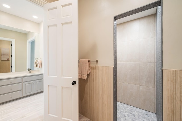 bathroom featuring recessed lighting, vanity, a walk in shower, and wainscoting