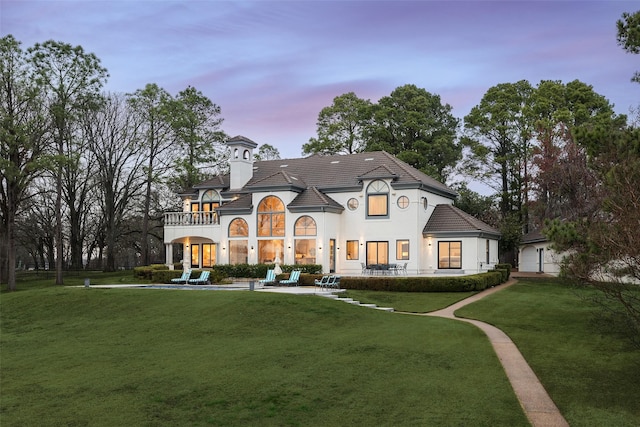 french country home featuring stucco siding, a lawn, and a tiled roof