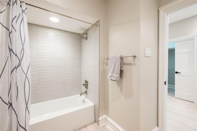 full bath featuring wood finished floors, baseboards, and shower / bath combo with shower curtain