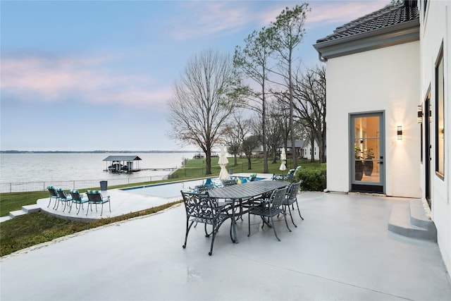 view of patio featuring a water view, fence, and outdoor dining space