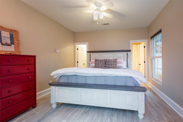 bedroom with ceiling fan, wood finished floors, visible vents, and baseboards