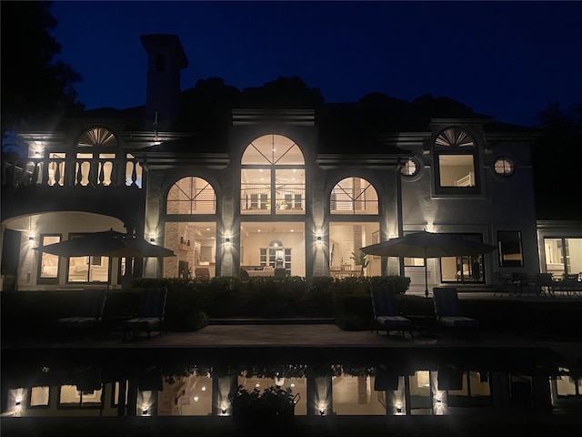 back of house at twilight featuring a patio area and an outdoor pool