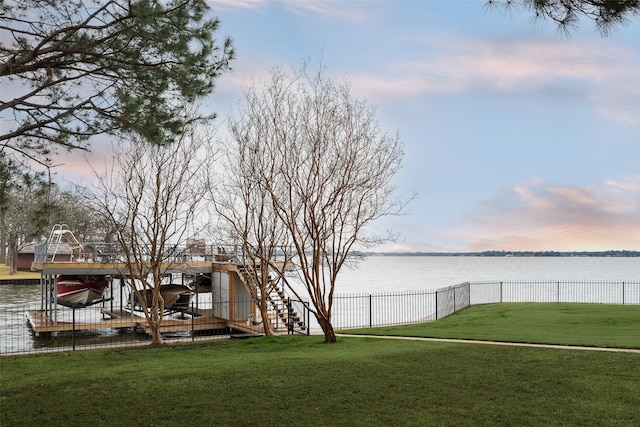 view of yard featuring a dock, a water view, and fence