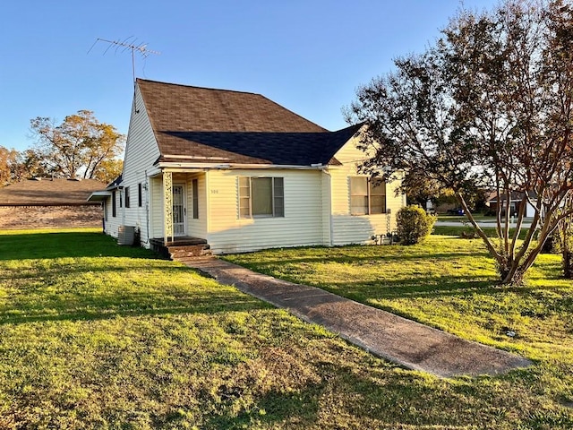 view of front facade featuring central AC, a front lawn, and a shingled roof