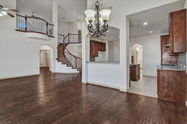 unfurnished living room featuring arched walkways, visible vents, baseboards, and stairs