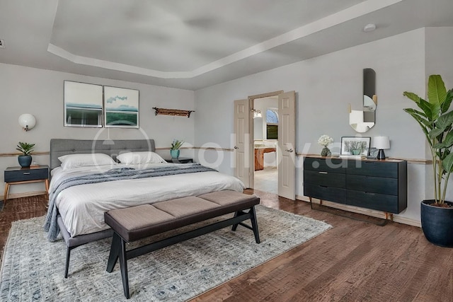 bedroom featuring wood finished floors, multiple windows, a raised ceiling, and baseboards