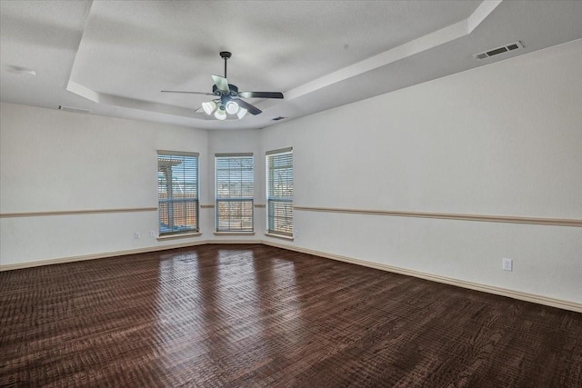 unfurnished room with ceiling fan, a raised ceiling, visible vents, and baseboards