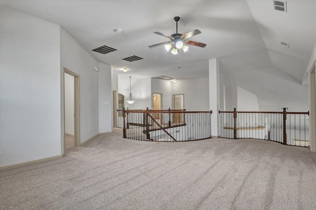 carpeted spare room with ceiling fan, vaulted ceiling, and visible vents