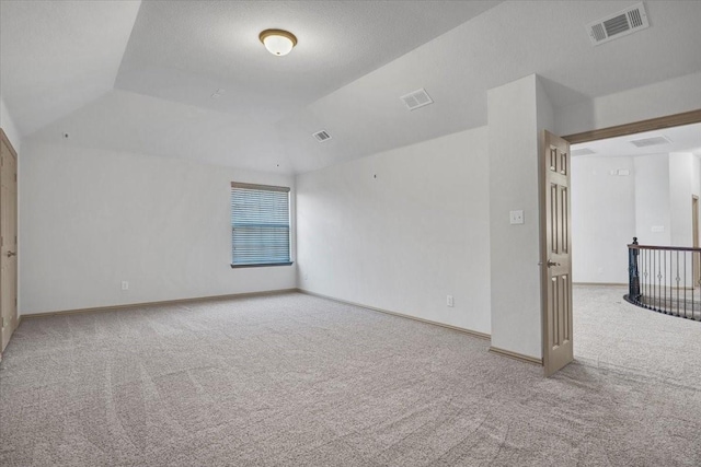 unfurnished room featuring carpet floors, baseboards, visible vents, and vaulted ceiling