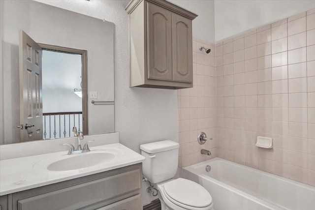 bathroom with a textured wall, tub / shower combination, vanity, and toilet