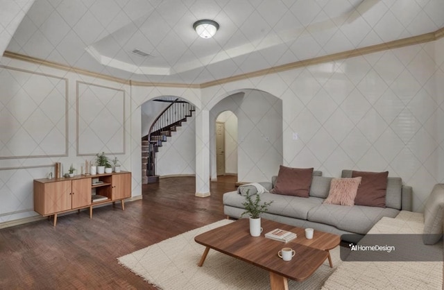 living area with arched walkways, visible vents, stairway, dark wood-type flooring, and ornamental molding