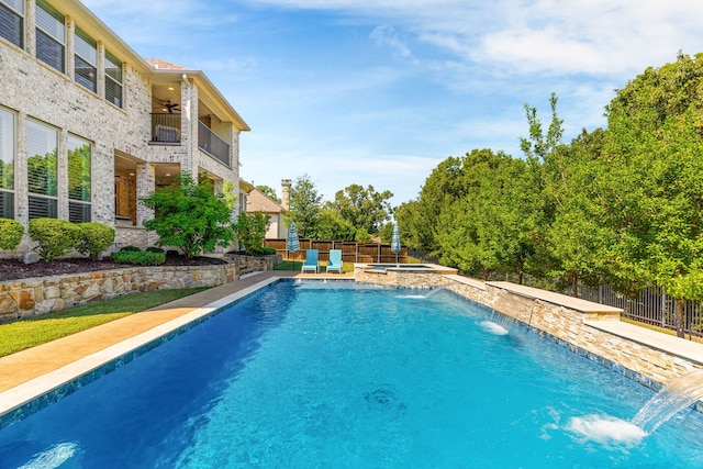 view of swimming pool with a fenced backyard, a pool with connected hot tub, and a ceiling fan