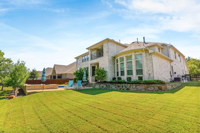 rear view of property with a yard, brick siding, a patio, and fence