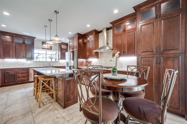 kitchen featuring decorative backsplash, appliances with stainless steel finishes, a sink, a kitchen island, and wall chimney exhaust hood