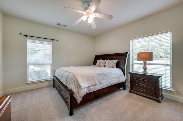 bedroom with baseboards, multiple windows, visible vents, and light colored carpet