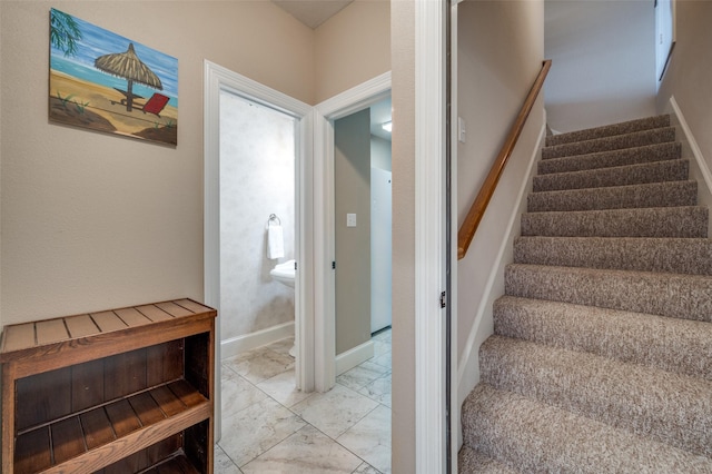 staircase featuring marble finish floor and baseboards