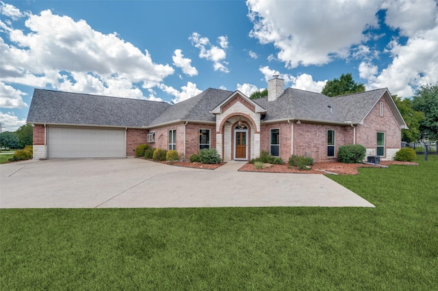 view of front of home featuring an attached garage, brick siding, concrete driveway, a front lawn, and a chimney