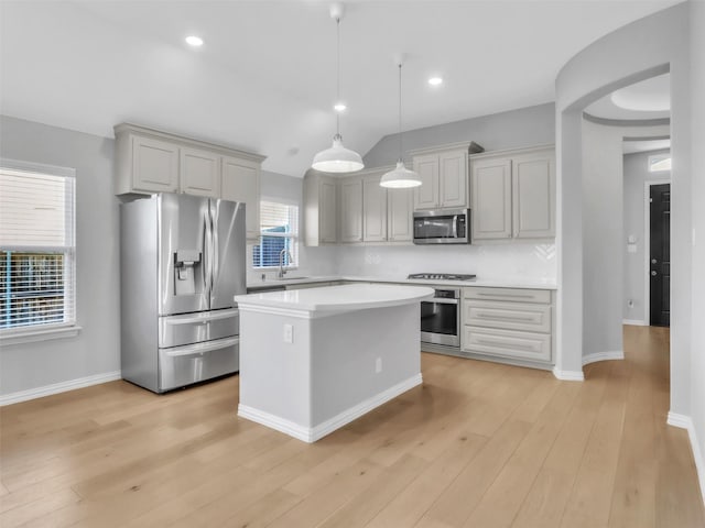 kitchen with stainless steel appliances, light countertops, backsplash, a sink, and light wood-type flooring