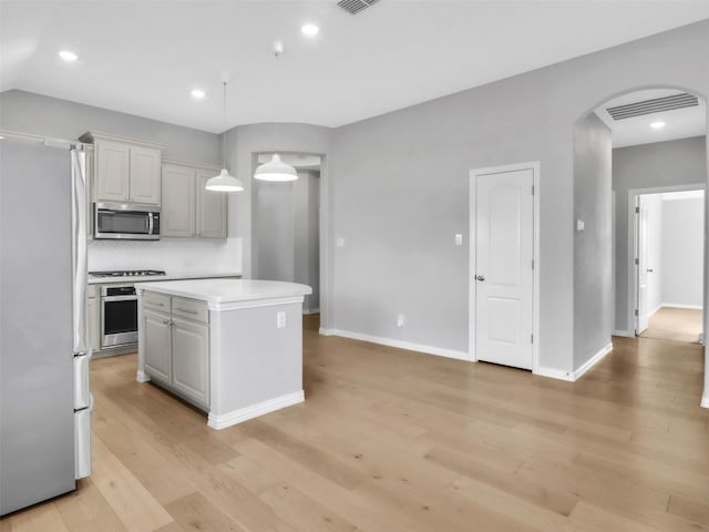 kitchen with visible vents, arched walkways, appliances with stainless steel finishes, light countertops, and light wood-style floors