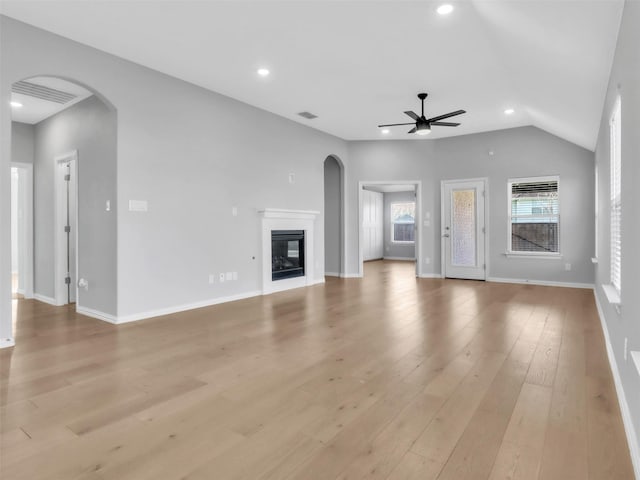 unfurnished living room with arched walkways, ceiling fan, light wood-style flooring, recessed lighting, and a glass covered fireplace