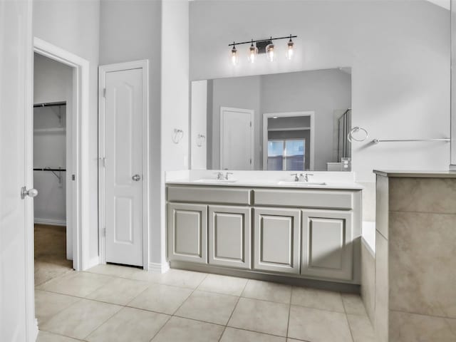 bathroom featuring double vanity, tile patterned flooring, a spacious closet, and a sink